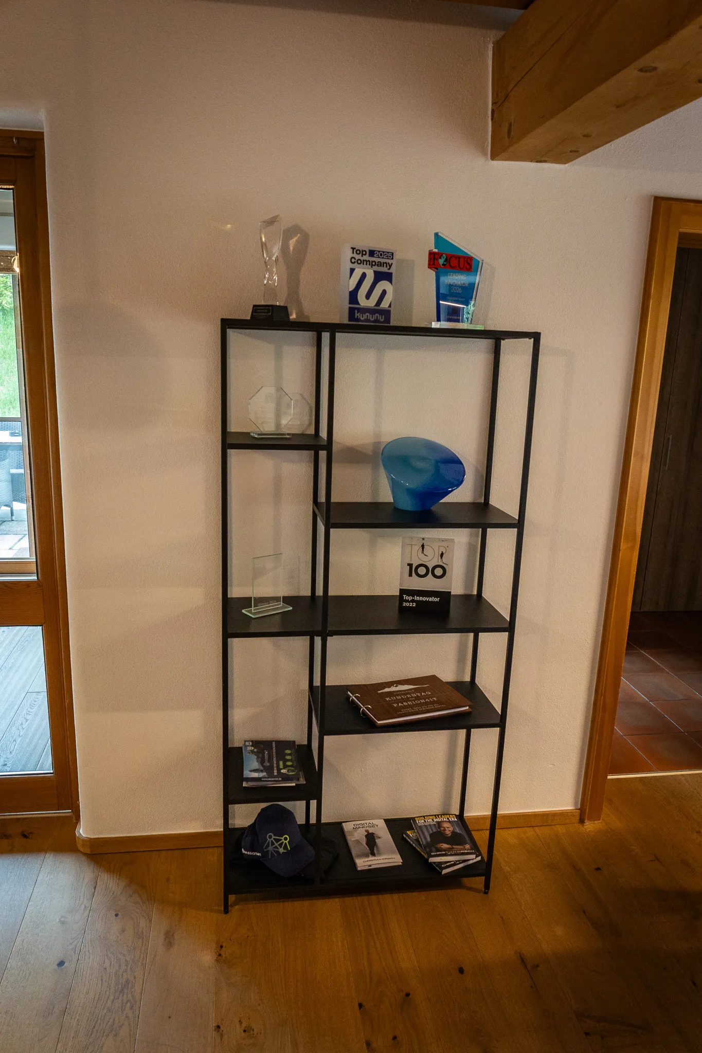 Award-Regal im PASSION4IT-Office: Pokale, Innovator-Trophäen, kununu-Top-Company-Schild und FOCUS-Auszeichnung auf einem Stahl-Regal vor heller Wand.